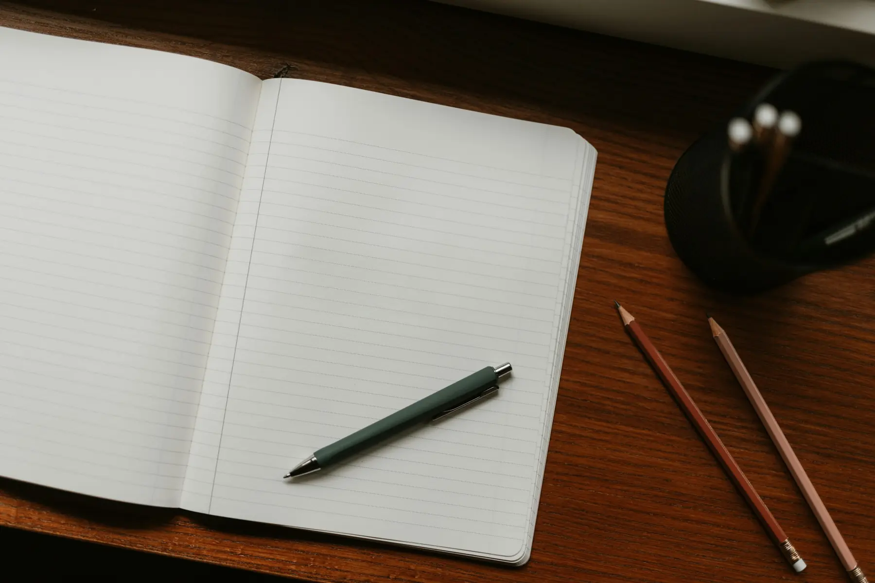 Caderno aberto com caneta e lápis sobre uma mesa