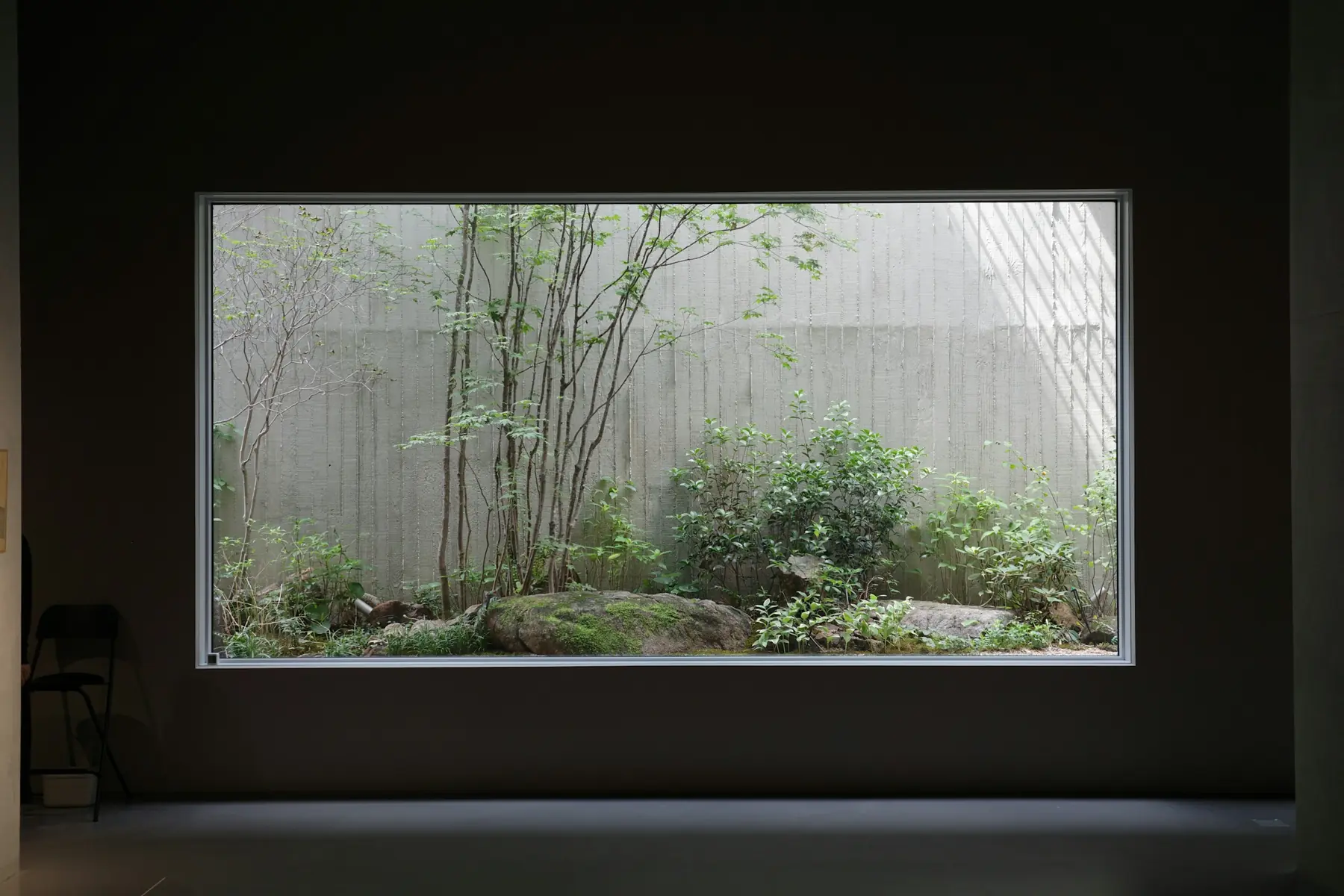 Sala vazia com uma grande janela retangular voltada para um jardim