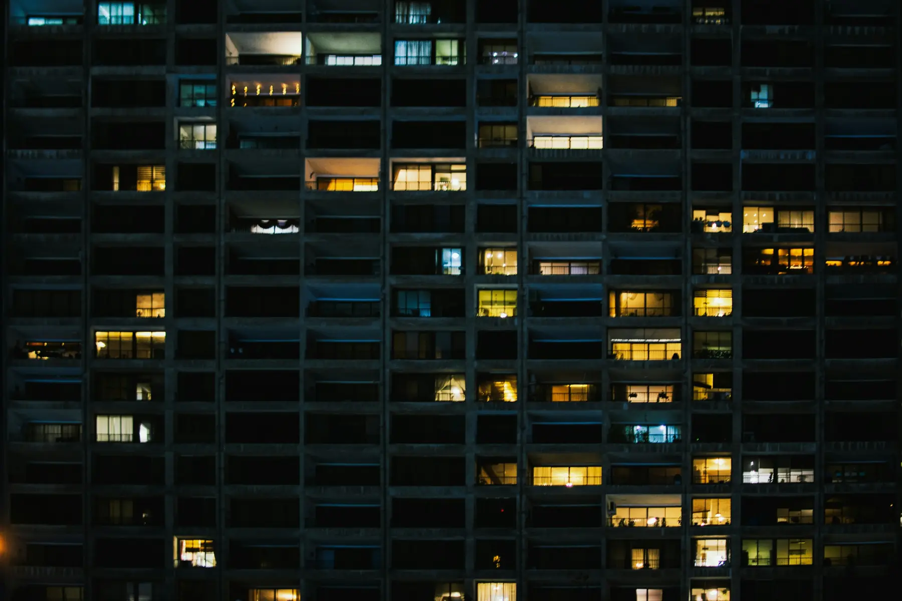 Fachada de prédio residencial à noite, com janelas acesas
