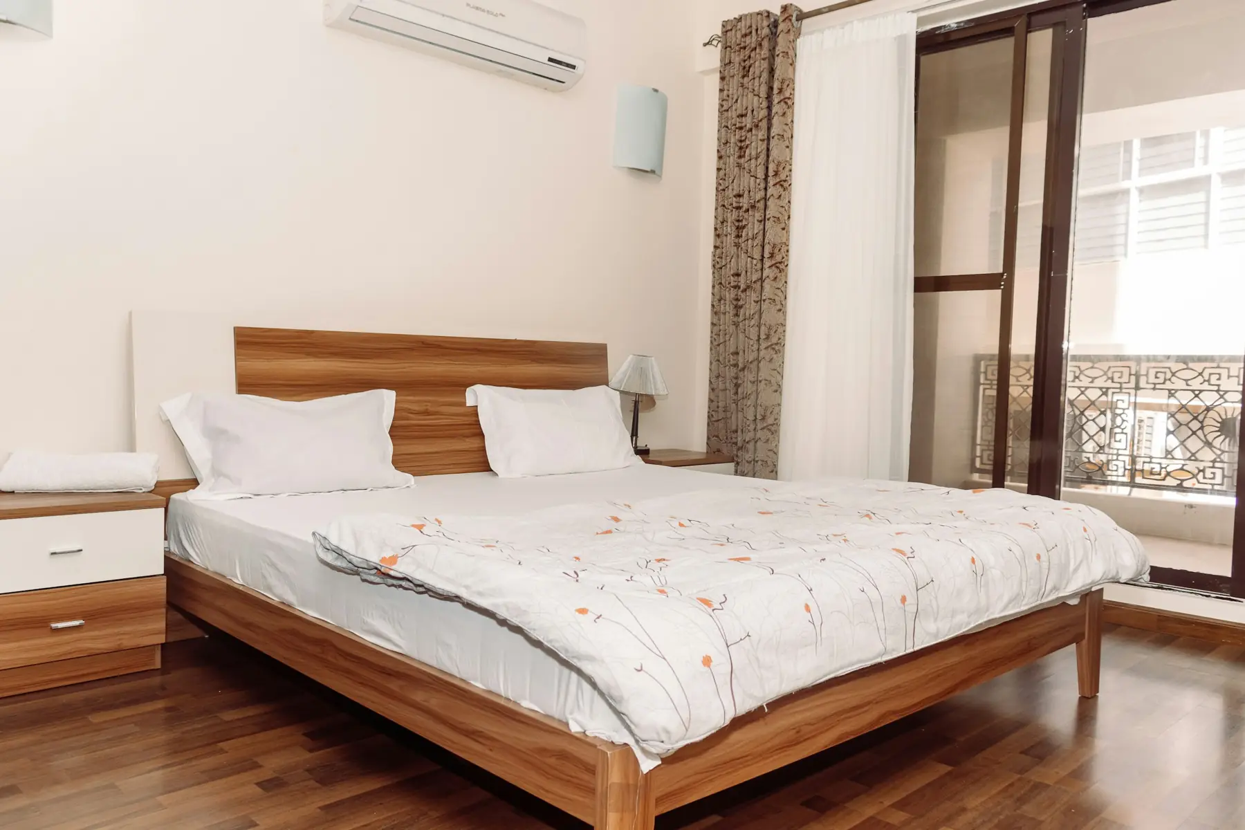 Quarto de apartamento arrumado, com cama de casal e porta para a varanda