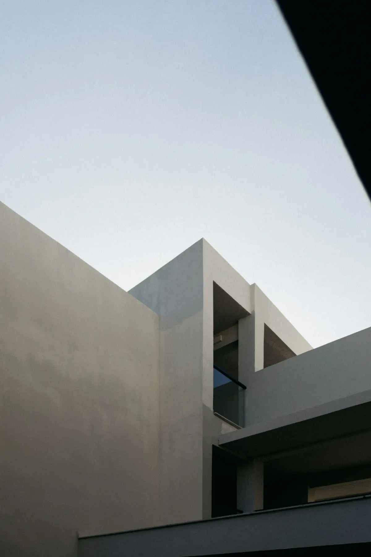 Volumes brancos de um edifício contemporâneo com recortes contra o céu